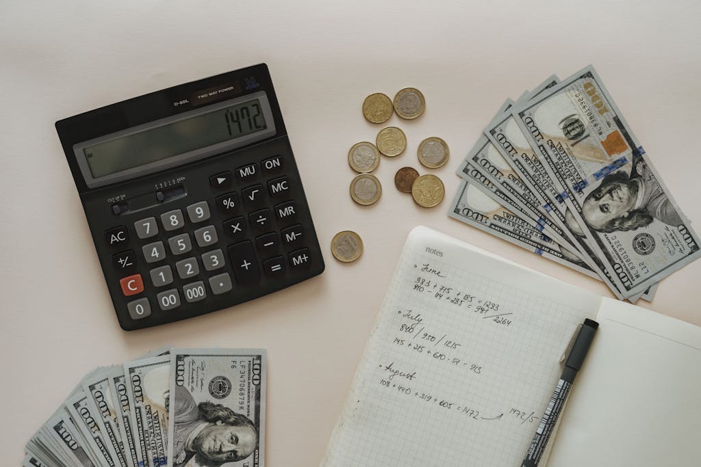 Black Calculator beside Coins and Notebook