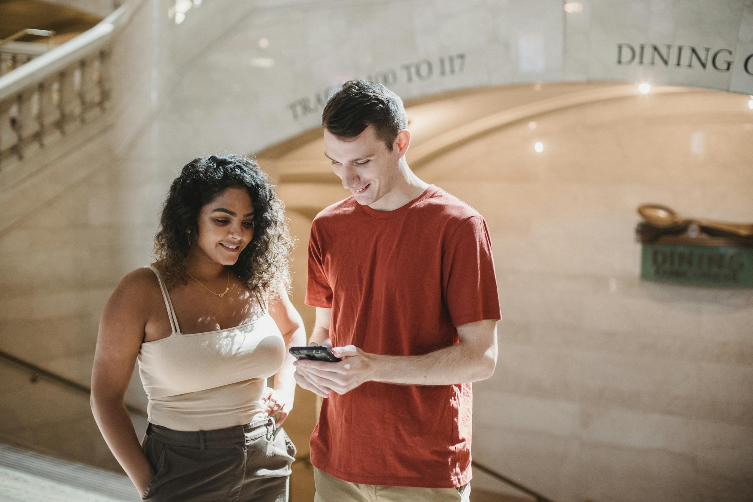 Positive young multiethnic couple browsing smartphone during trip in New York