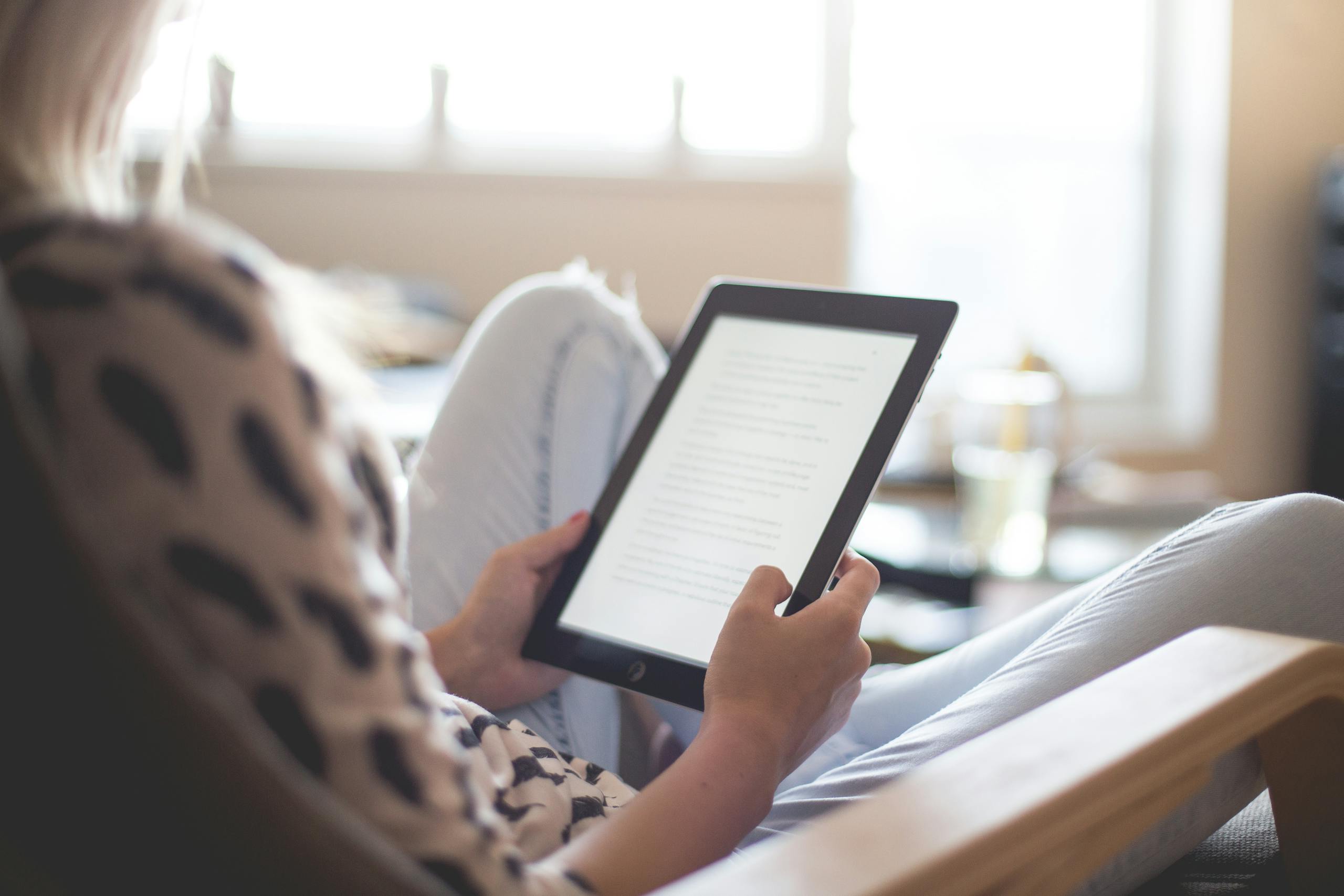 Woman Sitting on Chair Using Black Ipad. Must-Read Books for Digital Nomads