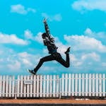 Man Jumping over White Fence